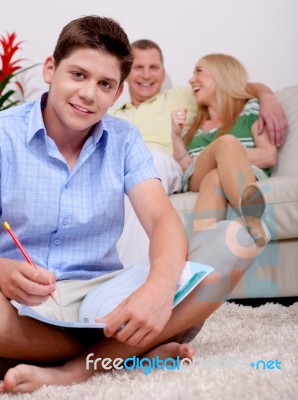 Young Smiling Teenager Sitting With His Book In Living Room Stock Photo