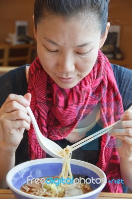 Young Woman Eating Noodles Stock Photo
