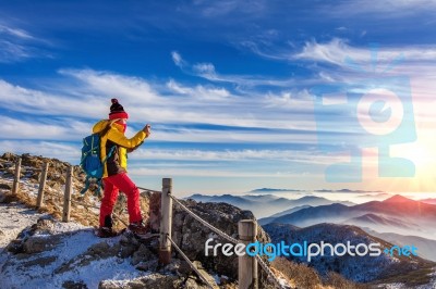 Young Woman Hiker Taking Photo With Smartphone On Mountains Peak In Winter Stock Photo