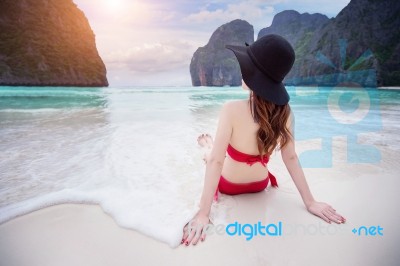 Young Woman In Red Bikini Sitting On The Beach Stock Photo