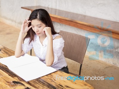 Young Woman Reading Book Or Magazine On Wood Table Stock Photo