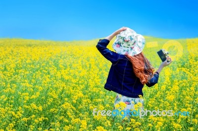 Young Woman Standing In Yellow Rapeseed Field Stock Photo
