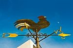 A Cockerel Wind Vane Against Blue Sky Stock Photo