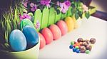 A Few Colorful Easter Eggs At The Green Garden On A Plant With Colorful Flowers And Candies And Chocolate Happy Easter Stock Photo