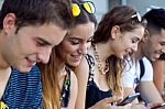 A Group Of Students Having Fun With Smartphones After Class Stock Photo