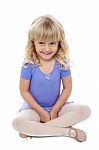 Adorable Kid Sitting With Crossed Legs On The Floor Stock Photo