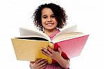 Adorable School Girl Reading A Book With A Smile Stock Photo