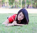 Asia Young Woman Lying On Grass Writing Book Stock Photo
