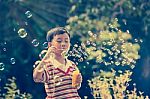 Asian Child Blowing Soap Bubbles, Nature Background. Vintage Pic Stock Photo