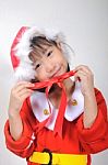 Asian Little Girl Dressed In Santa Claus Holding Red Ribbon Stock Photo