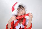 Asian Little Girl Dressed In Santa Claus Holding Red Ribbon Stock Photo