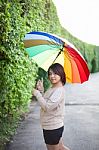 Asian Woman Holding An Umbrella On The Sidewalk Stock Photo