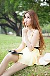 Asian Woman Sitting In The Park And Thinking Stock Photo