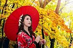 Asian Woman Wearing Traditional Japanese Kimono With Red Umbrella In Autumn Stock Photo