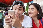 Asian Younger Man And Woman Watching On Smart Phone Use For People And Digital Technology ,wifi And Internet Connection Stock Photo