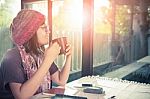 Asian Younger Woman And Hot Coffee Mug In Hand Smiling With Happiness Emotion Sitting Beside Mirror Window Against Beautiful Sun Light ,process Warming Color Mood And Tone Stock Photo