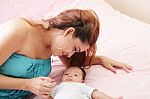 Attractive Mother Lying With Her Baby On The Bed At Home Stock Photo