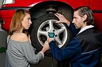 Auto Mechanic And Female Trainee Changing A Car Tyre In Garage Stock Photo