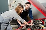 Auto Mechanic Guiding A Female Trainee In Garage Stock Photo
