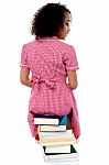 Back Pose Of A Girl Sitting On A Pile Of Books Stock Photo