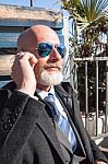 Bearded Businessman With Sunglasses Talking On Smartphone Stock Photo