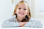 Beautiful Blonde Child Sitting At A Table In Kitchen Stock Photo