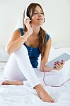 Beautiful Girl Listening To Music With Tablet On Sofa At Home Stock Photo