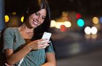 Beautiful Woman Use Her Phone In The City At Night Stock Photo