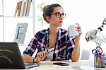 Beautiful Young Woman Drinking Coffee In Her Office Stock Photo