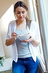 Beautiful Young Woman Eating Cereals At Home Stock Photo