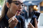 Beautiful Young Woman Making Up Using A Smart Phone As A Mirror Stock Photo