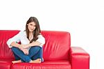 Beautiful Young Woman Sitting On Red Sofa Stock Photo