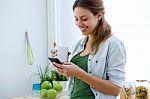Beautiful Young Woman Using Her Mobile Phone And Enjoying Breakf Stock Photo