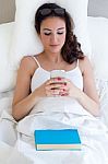 Beautiful Young Woman Using Her Mobile Phone In The Bed Stock Photo