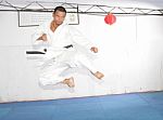 Black Belt Karate Man Jumping To Give A High Kick Stock Photo