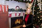 Blonde Female Sitting Next To Christmas Tree And Large Gift Stock Photo