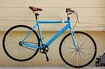 Blue Bicycle Hanging On Pale Yellow Cement Wall Stock Photo