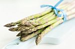 Bunch Of Fresh Asparagus On A Blue Wooden Cutting Board Stock Photo