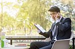 Business Man Using Mobile Phone And Hold A Report Paper  While S Stock Photo