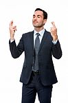 Businessman With Eyes Closed And Fingers Crossed Stock Photo