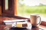 Cake And Cup Of Coffee On Wooden Table Near Window Sill. Time With Snacks Concept Stock Photo