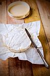 Camembert Cheese Wrapped In Paper With Vintage Knife On Wooden T Stock Photo