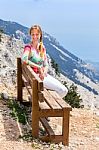 Caucasian Woman Sitting On Bench In Mountain Landscape Stock Photo
