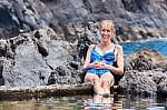 Caucasian Woman Sunbathing On Rocks At Natural Water Stock Photo