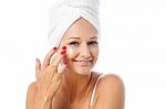 Charming Woman Applying Lotion On Her Face Stock Photo