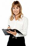 Cheerful Female Assistant Writing Notes Stock Photo