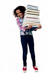 Cheerful Schoolgirl Carrying Pile Of Books Stock Photo