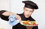 Chef Cleaning Edge Of Plate With Cloth Stock Photo