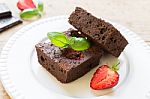 Chocolate Brownie Cake On White Plate Decorated With Strawberrie Stock Photo