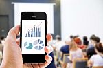 Close-up Hand Holding Mobile Phone With Analyzing Graph Stock Photo